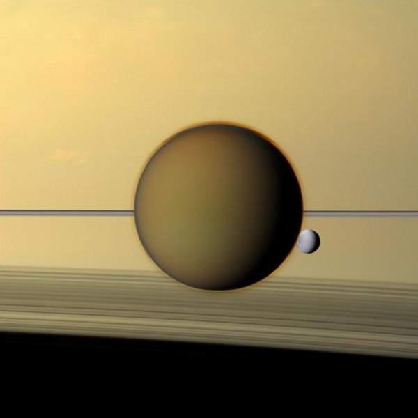 I globi di Titano e Dione si stagliano sul profilo degli anelli di Saturno; sotto, l’ombra striata degli anelli sull’atmosfera del pianeta. 