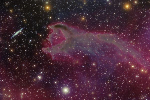 Un ectoplasma spaziale si protende verso un’ignara galassia, in un’apparente scena di predazione cosmica: ma è solo un’illusione, causata dalla mancanza di prospettiva del nostro sguardo verso il cielo.